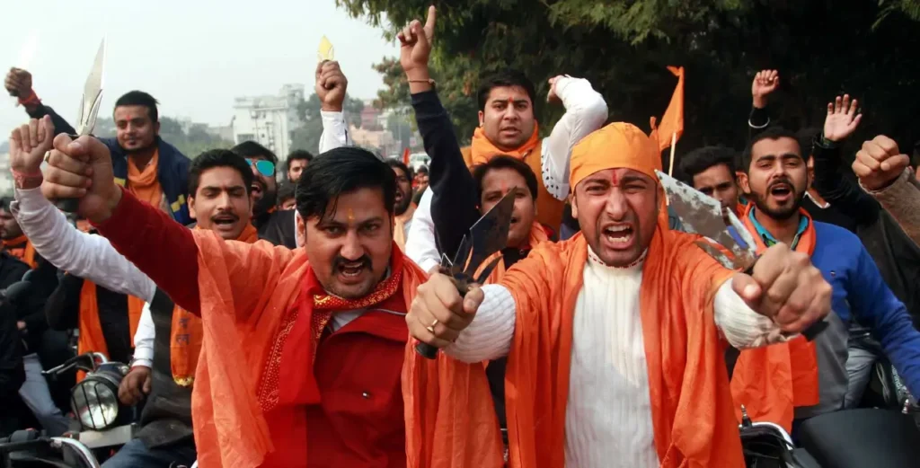 A group of Hindu extremists in saffron clothing holding weapons and shouting slogans during a rally in India