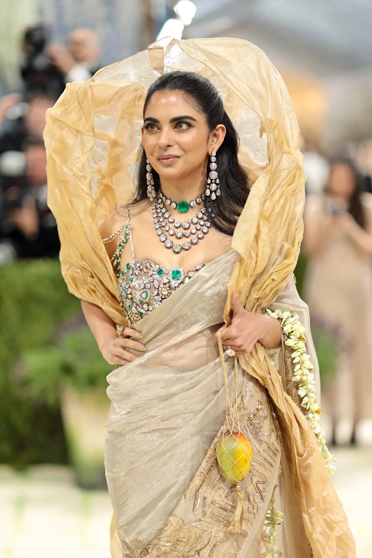 Isha Ambani at Met Gala 2026 wearing a custom gold Gaurav Gupta saree with over 1,800 carats of diamonds and emeralds, holding a mango sculpture purse, New York