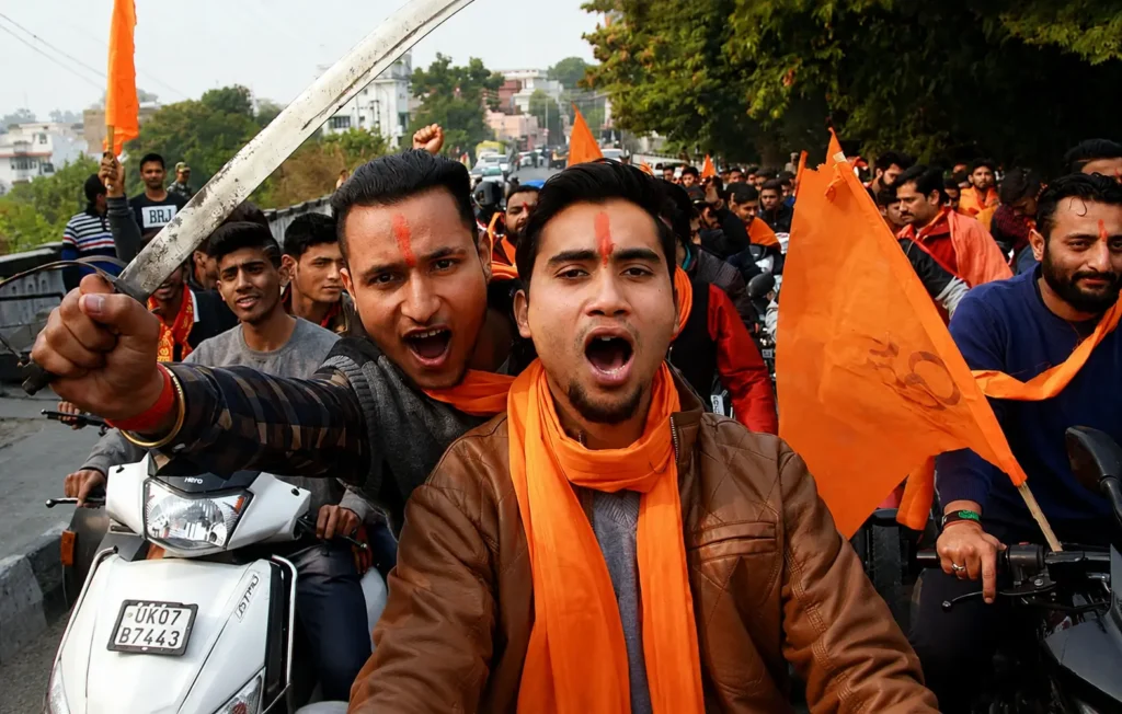 Hindu Extremist supporters riding motorcycles with saffron flags during a street rally in India amid debate over RSS outreach and rising hate crimes against minorities