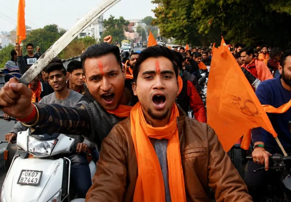 Hindu Extremist supporters riding motorcycles with saffron flags during a street rally in India amid debate over RSS outreach and rising hate crimes against minorities